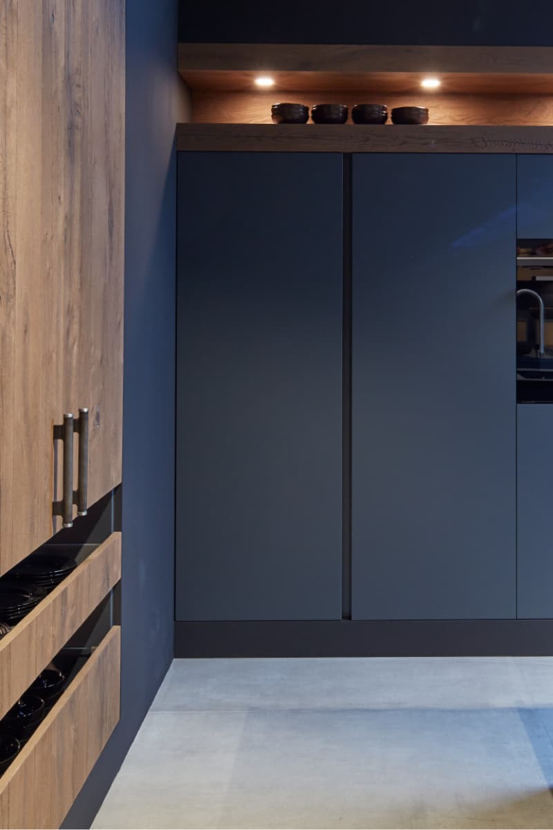 Armoires de cuisine noir mat avec rangements en bois naturel, éclairage LED intégré et design épuré