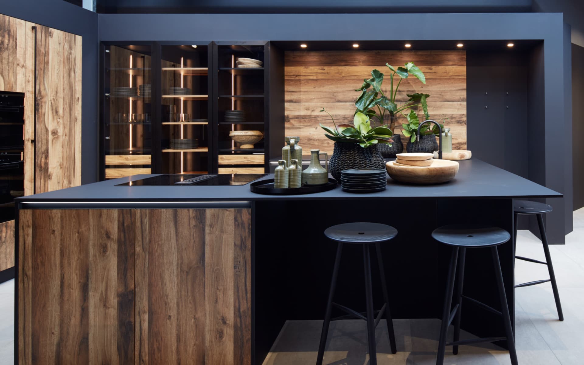 Cuisine équipée très haut de gamme moderne avec îlot central noir mat et façades en bois naturel, design contemporain avec vitrines et éclairage intégré