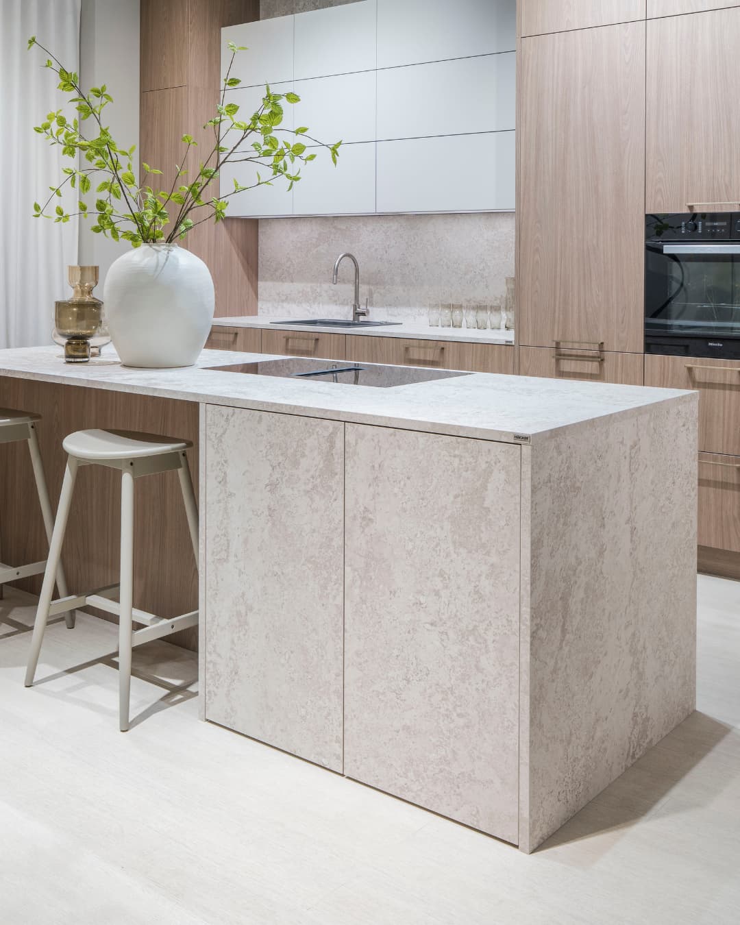 Cuisine style Japandi avec îlot en pierre claire, meubles en bois blond, décoration minimaliste et ambiance zen chaleureuse inspirée du design nordique