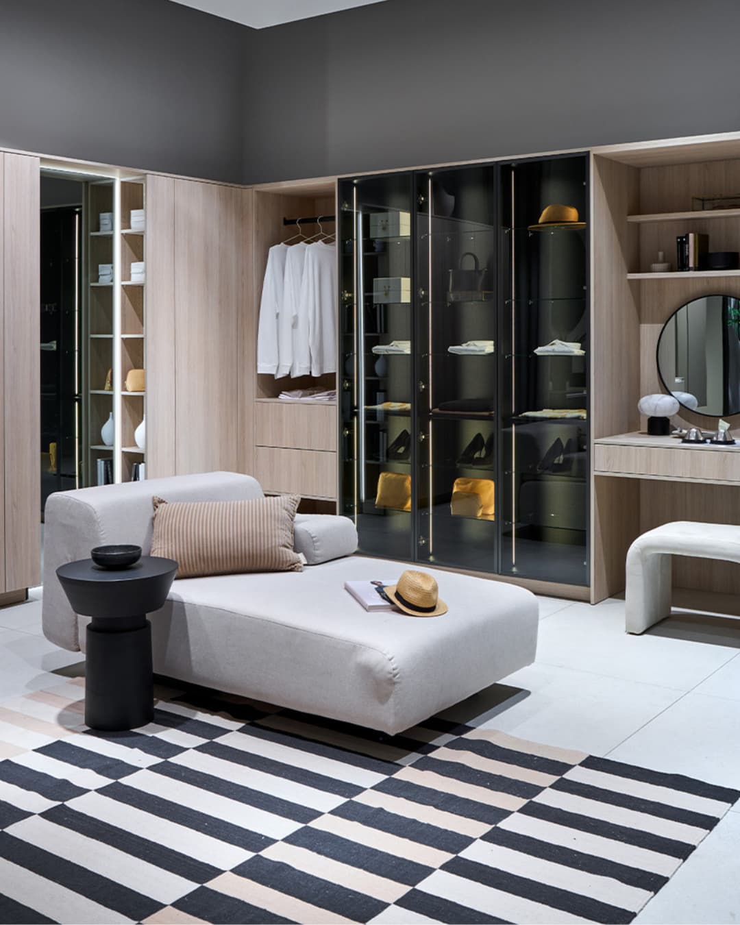 Dressing de chambre sur mesure avec vitrines en verre fumé, penderies ouvertes, meuble coiffeuse intégré et assise centrale dans un espace élégant et raffiné
