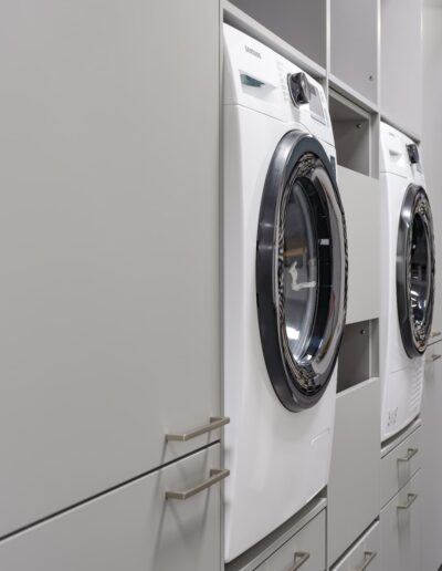 Buanderie sur mesure avec lave-linge intégré dans des meubles gris au showroom IDEO Bastogne