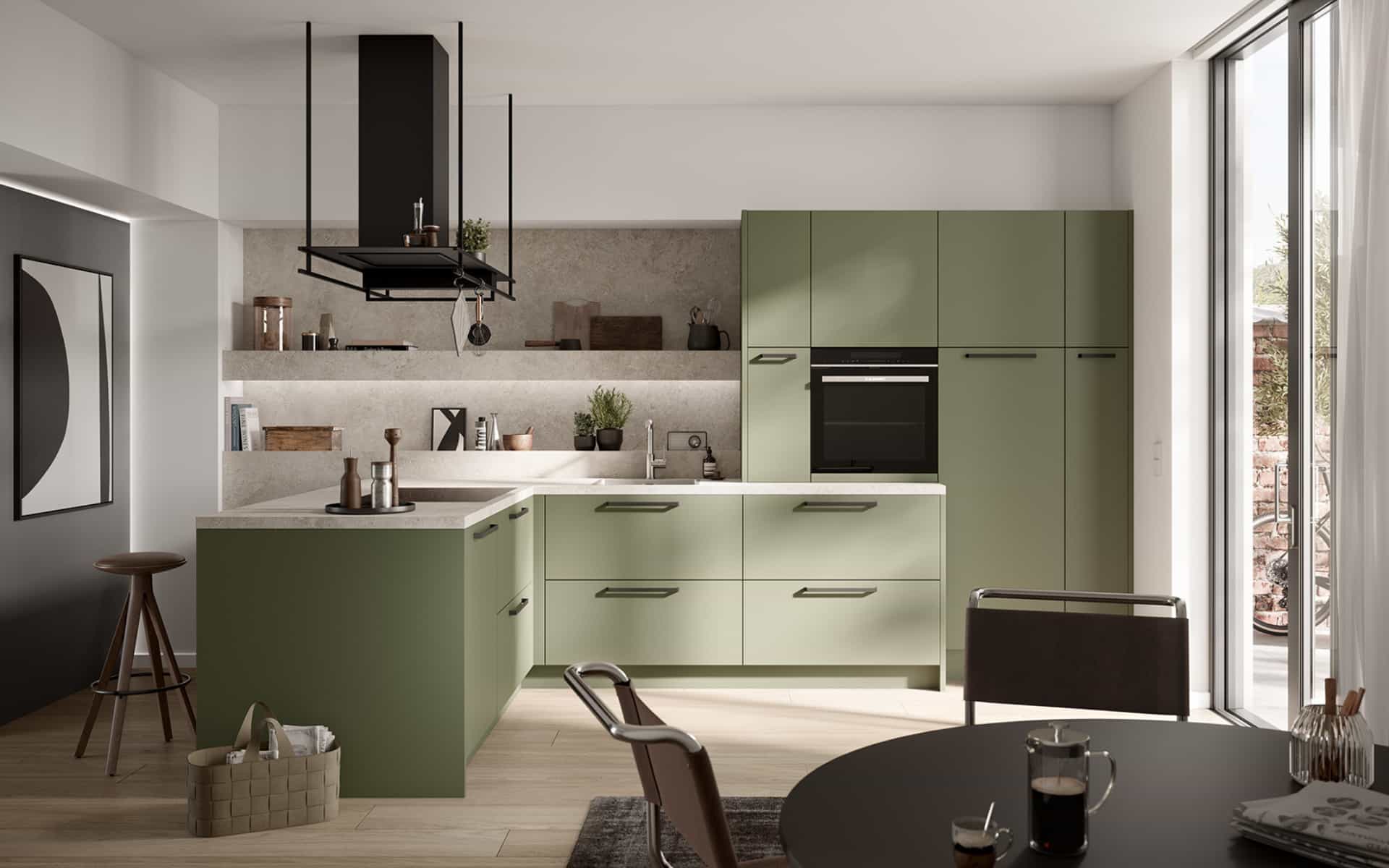 Cuisine moderne en L vert sauge mat avec îlot central, rangements intégrés et plan de travail clair. IDEO Cuisines